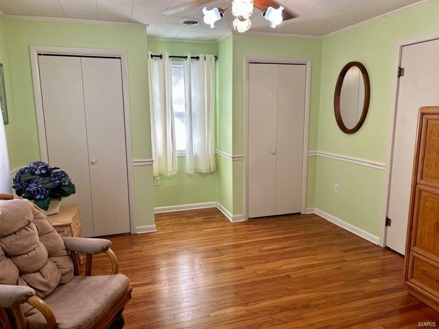 sitting room with crown molding, wood-type flooring, and a notable chandelier