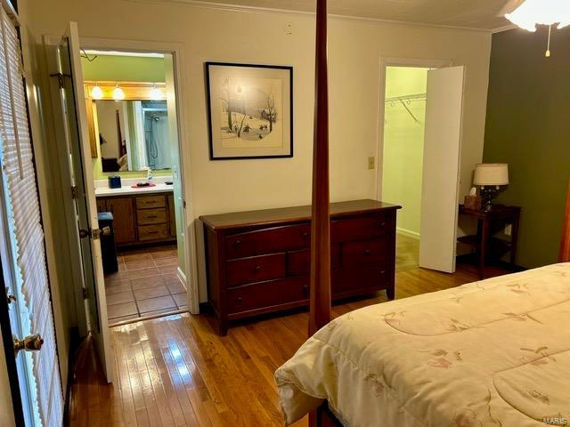 bedroom with light hardwood / wood-style flooring, ensuite bathroom, crown molding, a walk in closet, and a closet