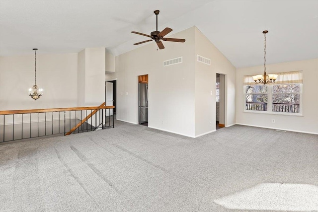 carpeted spare room featuring ceiling fan with notable chandelier and high vaulted ceiling