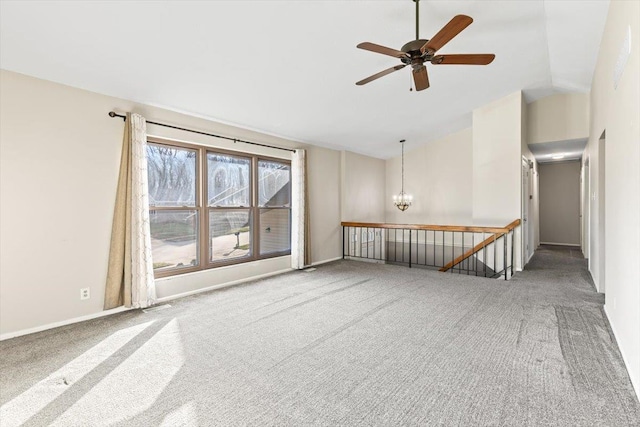 carpeted empty room featuring ceiling fan with notable chandelier and lofted ceiling