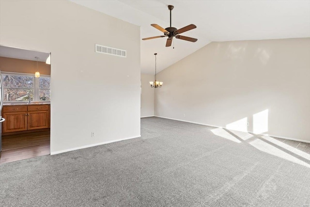 unfurnished living room featuring carpet flooring, ceiling fan with notable chandelier, and high vaulted ceiling