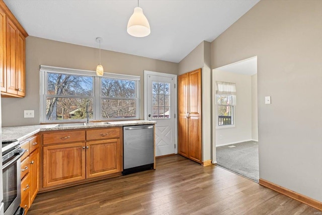 kitchen with sink, dark wood-type flooring, lofted ceiling, decorative light fixtures, and appliances with stainless steel finishes