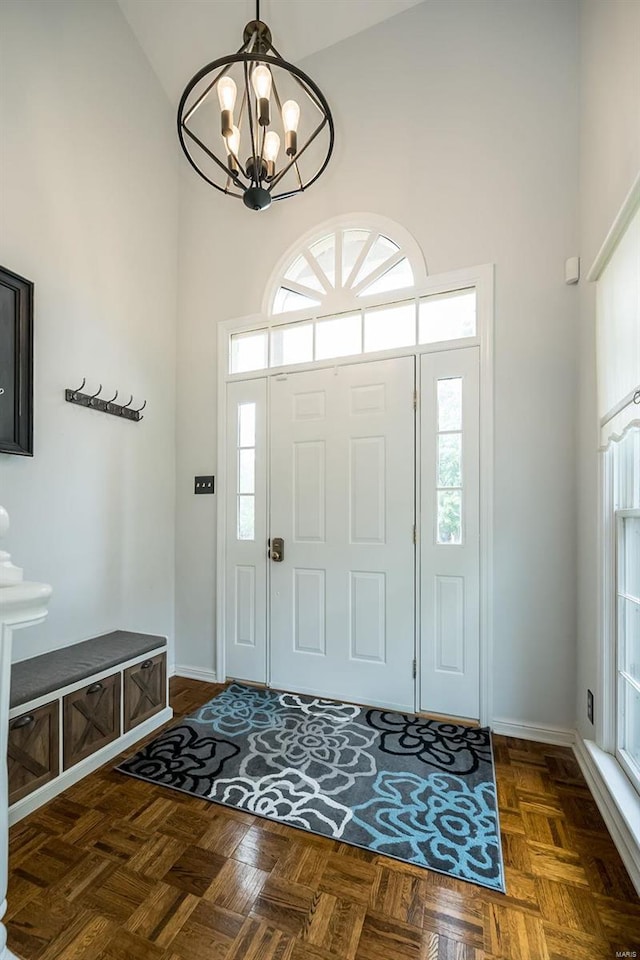 foyer entrance featuring dark parquet floors, a chandelier, and a high ceiling