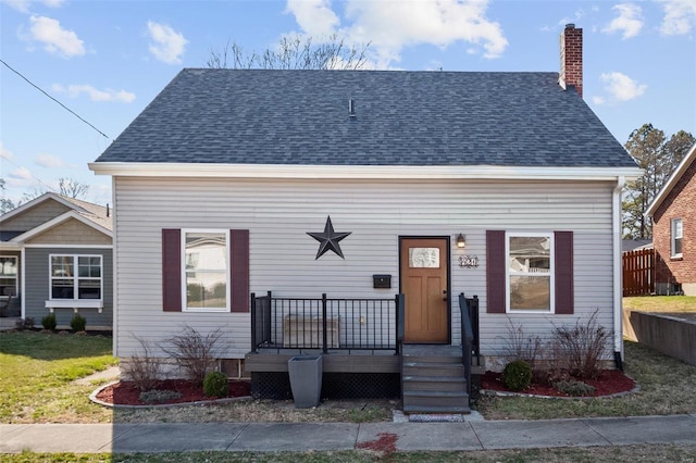 view of front of property with a deck, roof with shingles, and a chimney