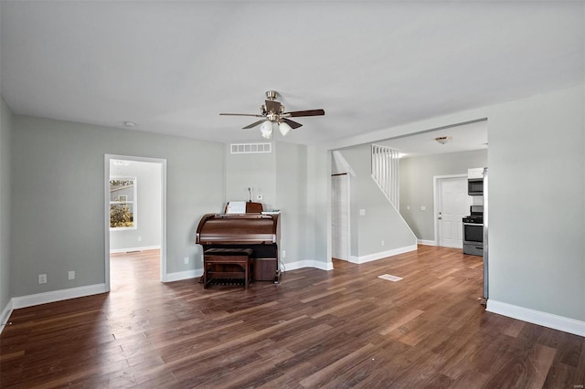 living area with visible vents, dark wood-type flooring, ceiling fan, baseboards, and stairway