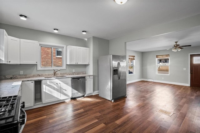 kitchen featuring light stone counters, dark wood finished floors, a sink, white cabinets, and appliances with stainless steel finishes