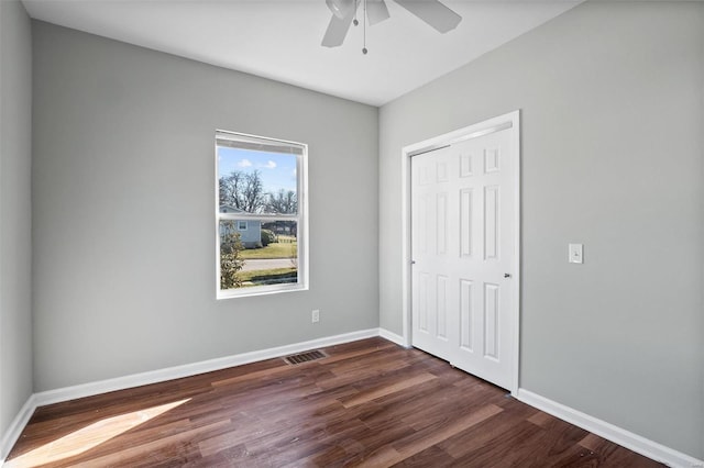 unfurnished bedroom with a ceiling fan, baseboards, visible vents, dark wood finished floors, and a closet