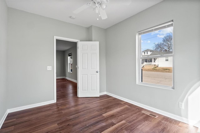 spare room featuring visible vents, baseboards, wood finished floors, and a ceiling fan