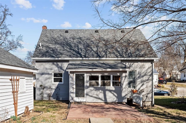 back of house with a yard, roof with shingles, a chimney, and a patio area