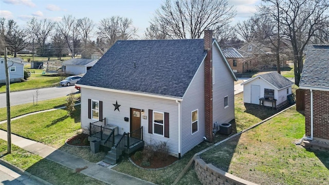 view of front of property featuring a front lawn, central air condition unit, a chimney, and a shingled roof