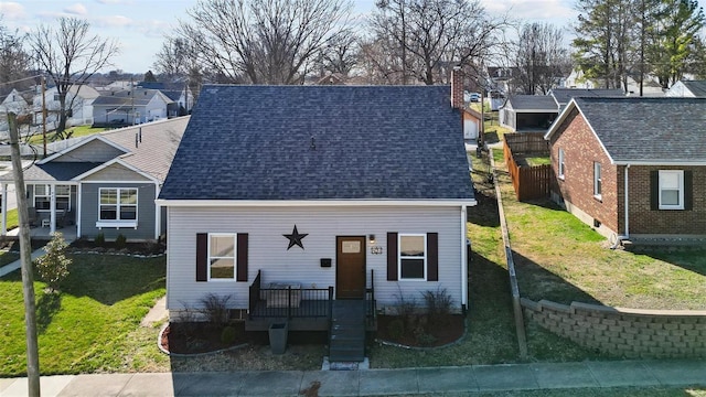 view of front of house featuring fence, a residential view, a front yard, a shingled roof, and a chimney