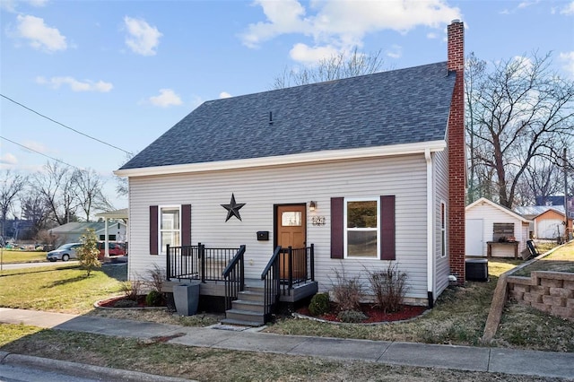 view of front of home featuring a front yard, roof with shingles, and a chimney