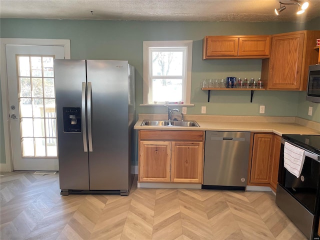 kitchen with stainless steel appliances, a textured ceiling, light parquet floors, and sink