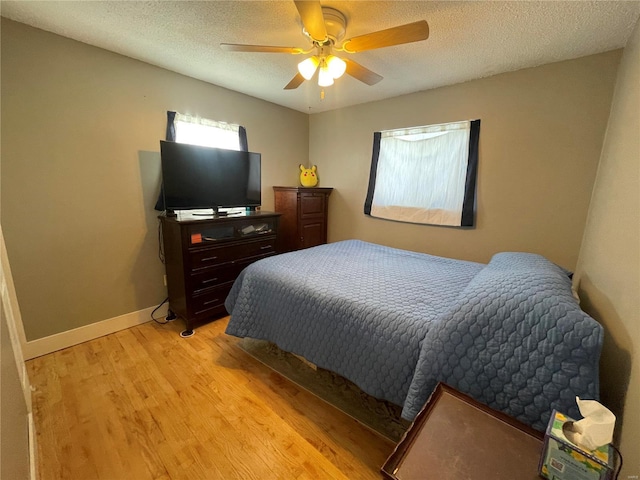 bedroom with a textured ceiling, ceiling fan, and light hardwood / wood-style flooring