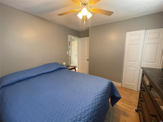 bedroom featuring ceiling fan, light wood-type flooring, a closet, and a textured ceiling