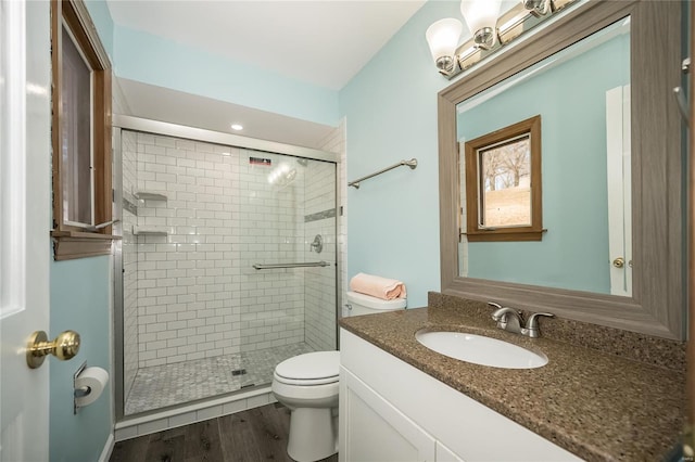 bathroom featuring vanity, toilet, a shower with shower door, and hardwood / wood-style floors