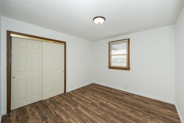 unfurnished bedroom with dark hardwood / wood-style flooring and a closet