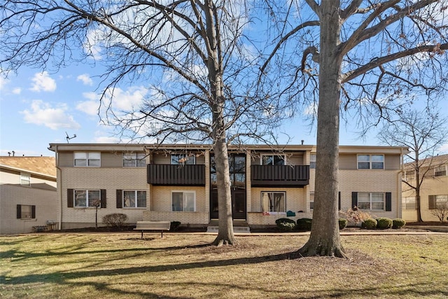 rear view of property featuring a balcony and a yard