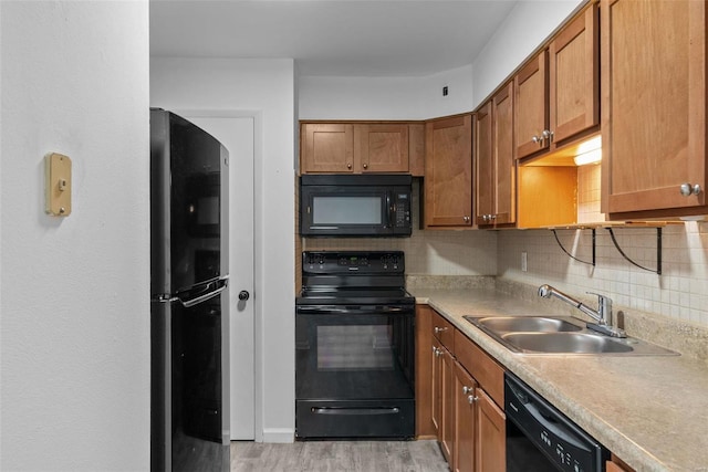 kitchen featuring sink, backsplash, light hardwood / wood-style flooring, and black appliances