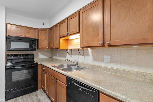 kitchen featuring sink, backsplash, black appliances, and light wood-type flooring