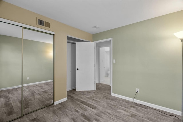 unfurnished bedroom with two closets and light wood-type flooring