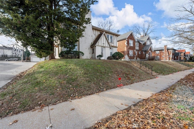 view of side of property with a garage, a yard, and an outdoor structure