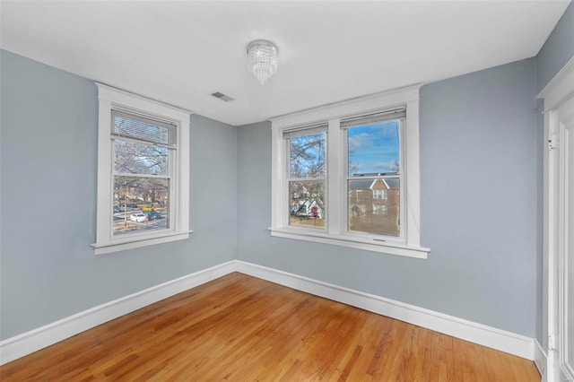 spare room featuring a chandelier and wood-type flooring