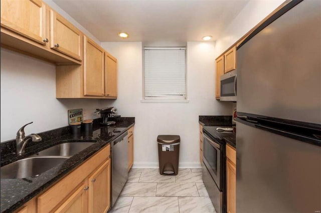 kitchen featuring dark stone counters, appliances with stainless steel finishes, light brown cabinets, and sink