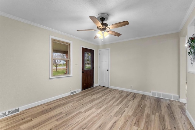 empty room with a textured ceiling, ceiling fan, light wood-type flooring, and crown molding