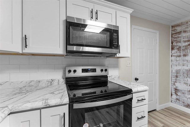 kitchen with light stone countertops, white cabinetry, appliances with stainless steel finishes, and light hardwood / wood-style flooring