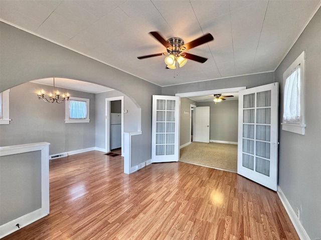 empty room with french doors, ceiling fan with notable chandelier, and light hardwood / wood-style floors