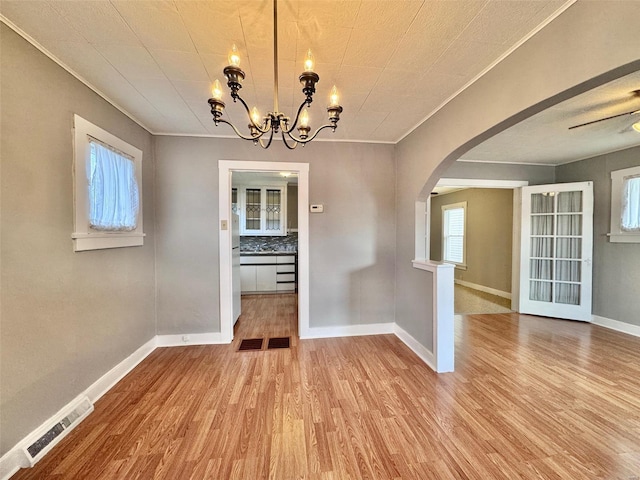 unfurnished dining area featuring crown molding, ceiling fan with notable chandelier, and light hardwood / wood-style flooring