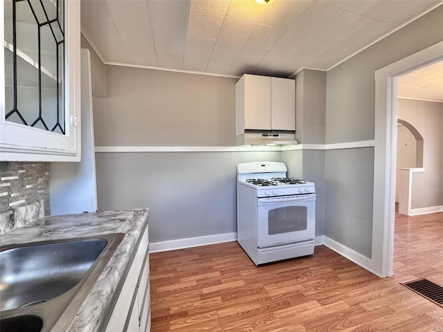 kitchen with gas range gas stove, white cabinetry, sink, backsplash, and light hardwood / wood-style flooring