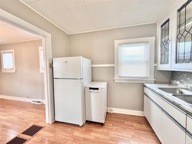 kitchen with white cabinetry, sink, white appliances, and light hardwood / wood-style flooring