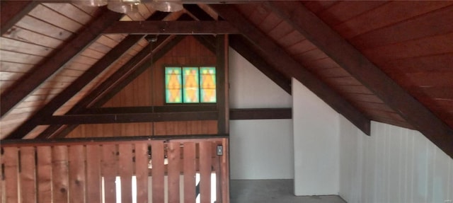 additional living space featuring wooden walls and lofted ceiling with beams