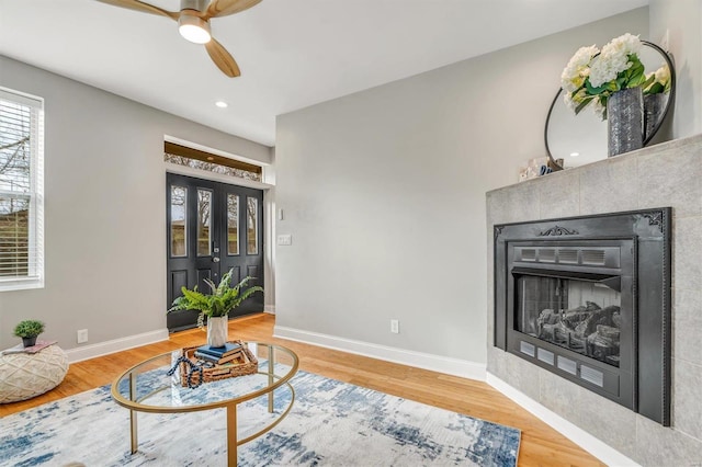 living area with a fireplace, ceiling fan, and hardwood / wood-style floors