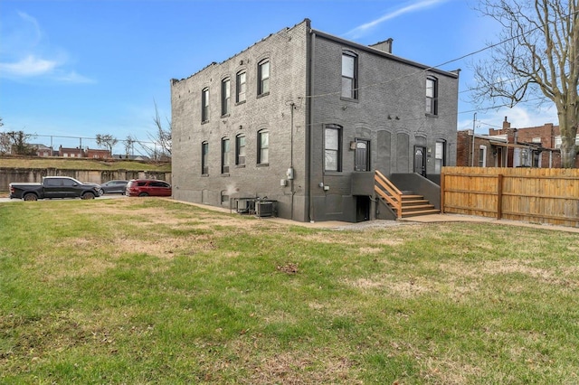 rear view of house featuring a lawn and central air condition unit