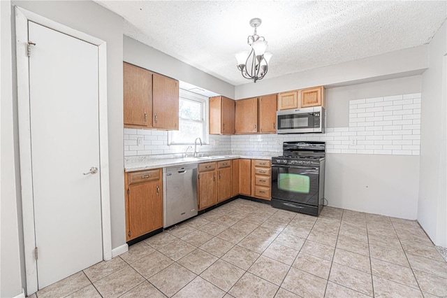 kitchen featuring sink, a textured ceiling, hanging light fixtures, appliances with stainless steel finishes, and backsplash