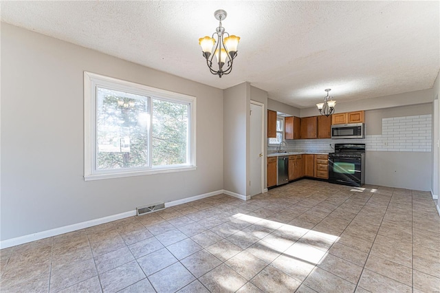 kitchen with appliances with stainless steel finishes, pendant lighting, a notable chandelier, and decorative backsplash