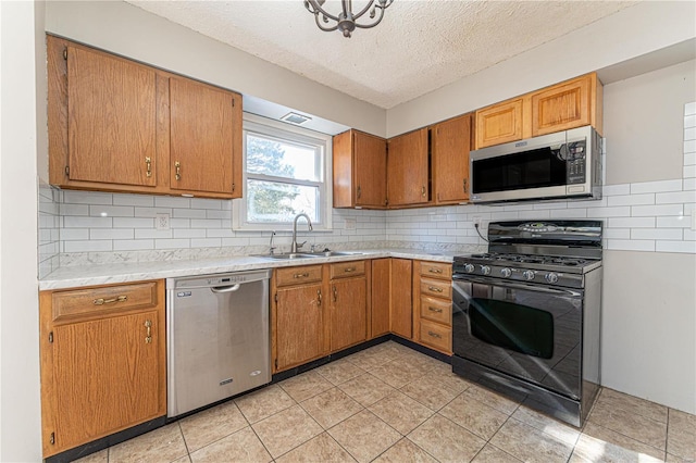 kitchen featuring sink, decorative backsplash, light tile patterned floors, stainless steel appliances, and a textured ceiling