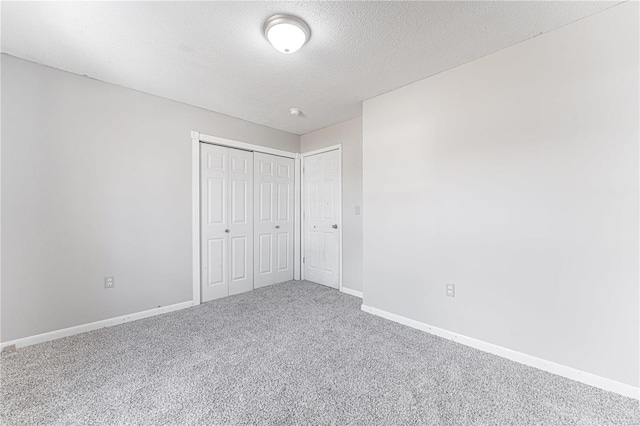 unfurnished bedroom with carpet, a textured ceiling, and a closet