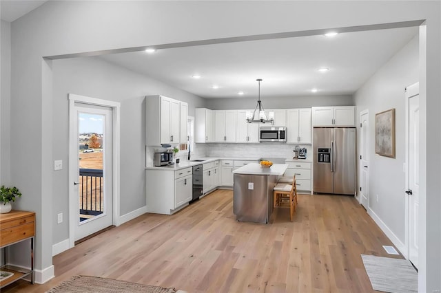 kitchen with white cabinetry, decorative light fixtures, stainless steel appliances, and a center island