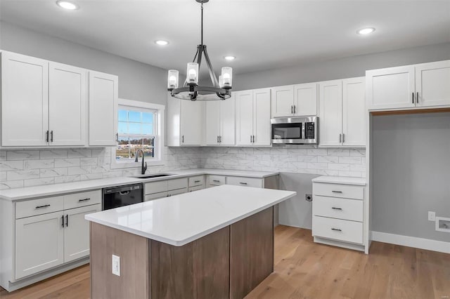 kitchen with decorative light fixtures, dishwasher, white cabinetry, sink, and a center island