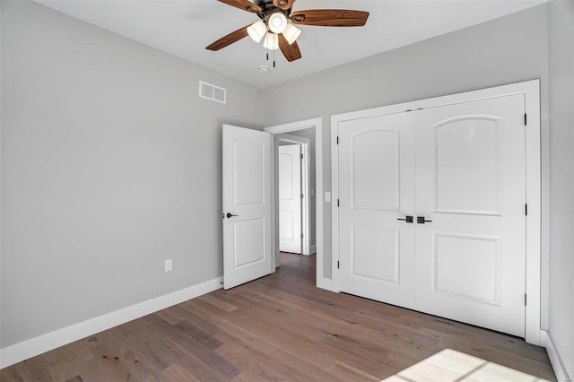 unfurnished bedroom with dark wood-type flooring, ceiling fan, and a closet