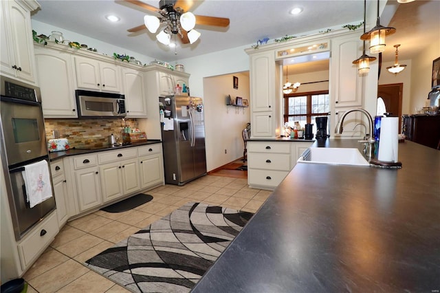 kitchen with sink, hanging light fixtures, light tile patterned floors, appliances with stainless steel finishes, and backsplash