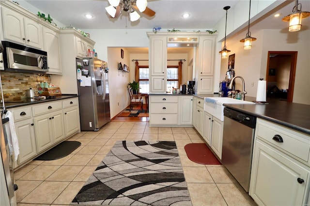 kitchen featuring sink, hanging light fixtures, light tile patterned floors, stainless steel appliances, and cream cabinets