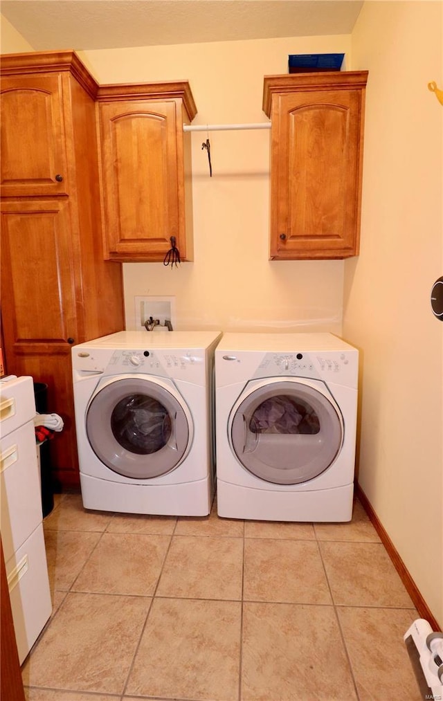 washroom featuring light tile patterned flooring, cabinets, and washer and dryer