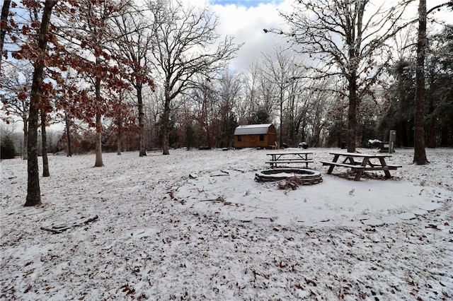 yard covered in snow featuring a storage unit and an outdoor fire pit