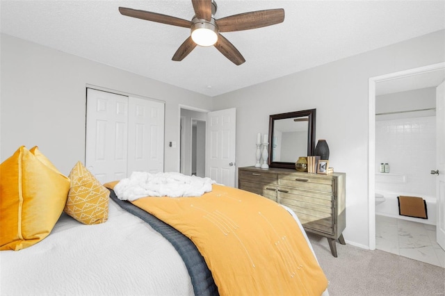 bedroom featuring a textured ceiling, ensuite bath, carpet floors, a closet, and ceiling fan