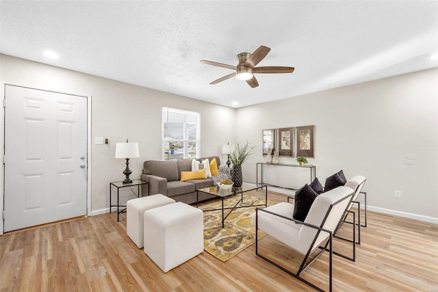 living room featuring ceiling fan, light hardwood / wood-style floors, and a textured ceiling